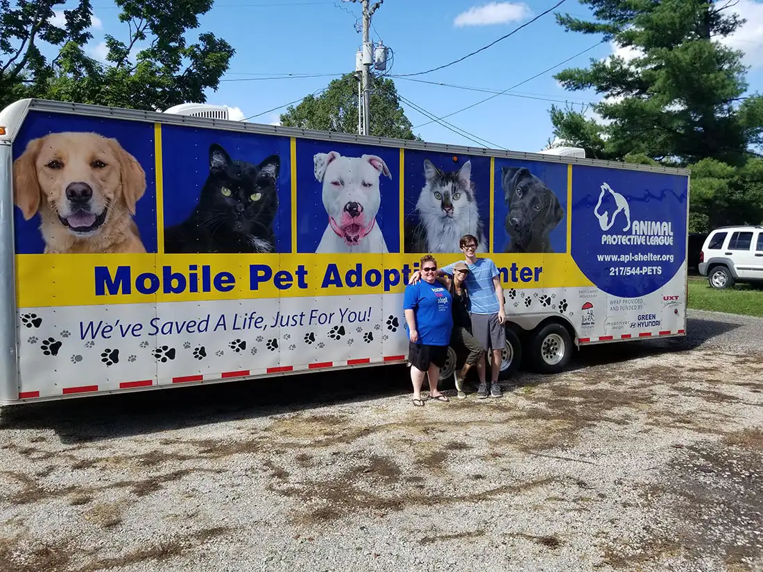 Christina Yoc Agency | Central IL team posing in front of pet adoption popup for community outreach
